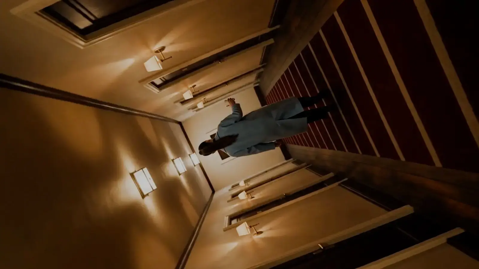 Frame from the corridor film: the camera rolls as she walks along the wall.